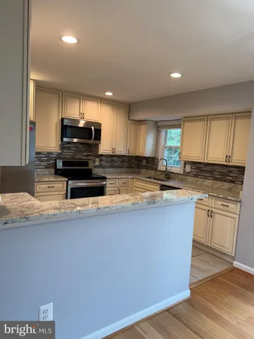 a kitchen with kitchen island granite countertop a stove a sink a refrigerator and a microwave