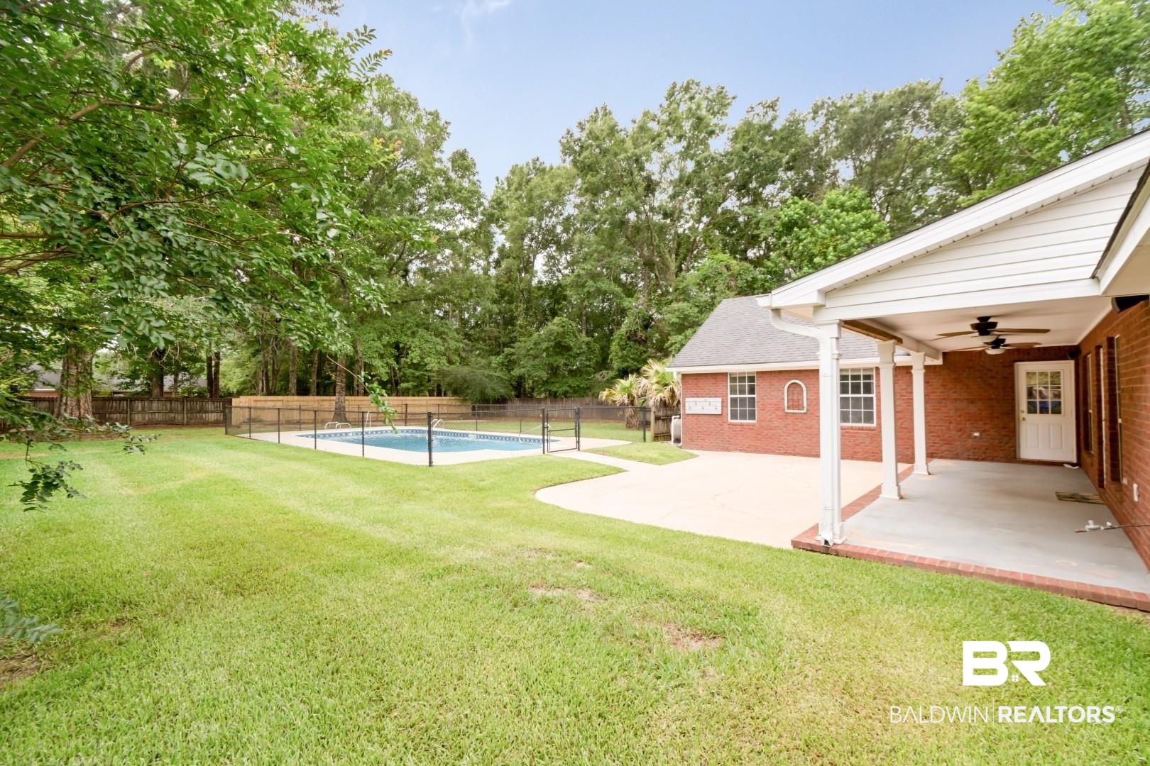 10691 Hunters Ridge Drive Mobile, AL 36695 - Photo 31 of 37 Expansive backyard featuring a fenced-in swimming pool, a covered patio with ceiling fans, a red brick exterior, and mature trees