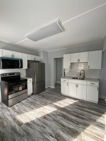 a kitchen with granite countertop a refrigerator oven a stove and a sink with wooden floor