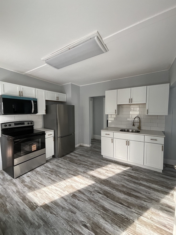 25 Malden Street, Unit 2 Springfield, MA 01108 - Photo 3 of 10 a kitchen with granite countertop a refrigerator oven a stove and a sink with wooden floor