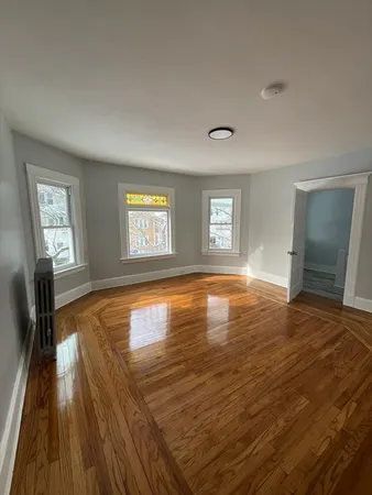 a view of empty room with window and wooden floor