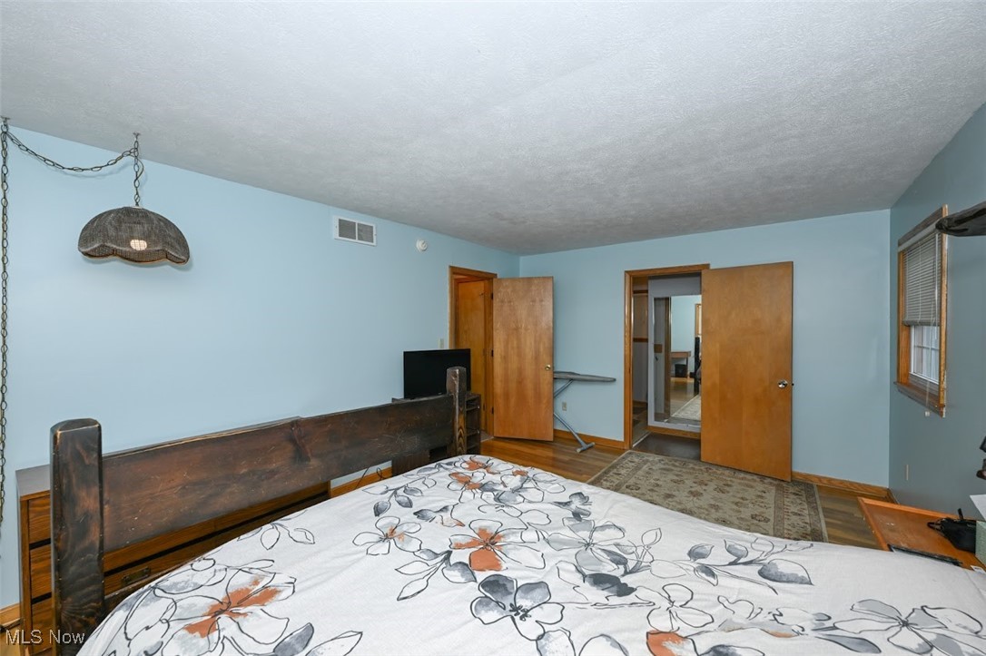 3305 Edington Road Akron, OH 44333 - Photo 18 of 46 Bedroom with visible vents, baseboards, a textured ceiling, and wood finished floors