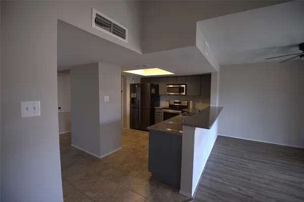 a kitchen with stainless steel appliances granite countertop a refrigerator and a wooden floor