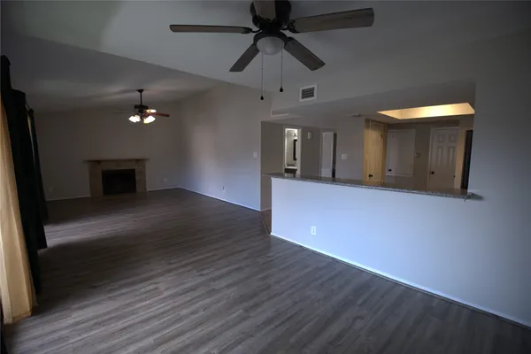 an empty room with wooden floor a ceiling fan and entryway