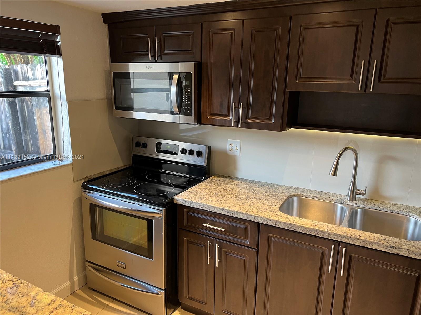 7009 Southwest 109th Place Miami, FL 33173 - Photo 5 of 7 a kitchen with a stove microwave and sink