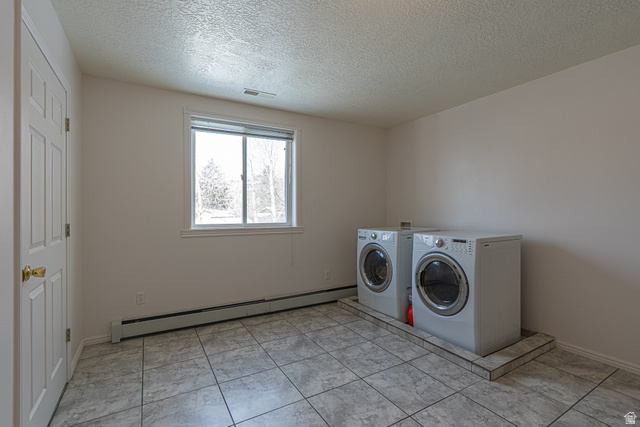 1045 Fox Farm Road Logan, UT 84321 - Photo 45 of 65 Washroom featuring a baseboard heating unit, washing machine and clothes dryer, and a textured ceiling