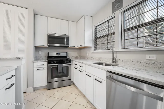 a kitchen with granite countertop a sink stainless steel appliances and cabinets