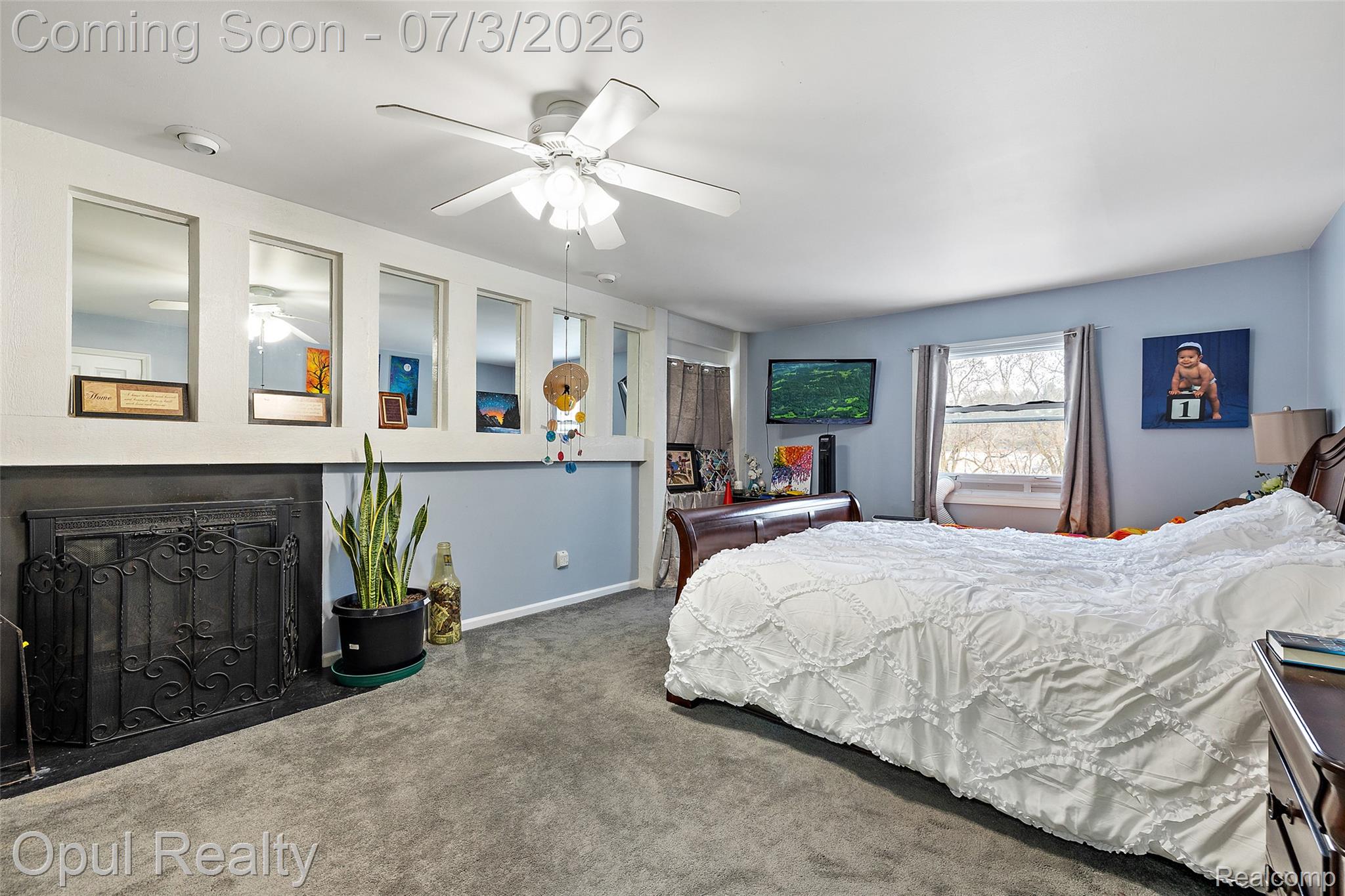 8855 Gross Road Dexter, MI 48130 - Photo 38 of 53 Carpeted room featuring a fireplace with an ornate iron screen, multiple recessed wall mirrors, a ceiling fan, and two windows