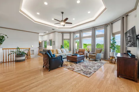 a living room with furniture large windows and wooden floor