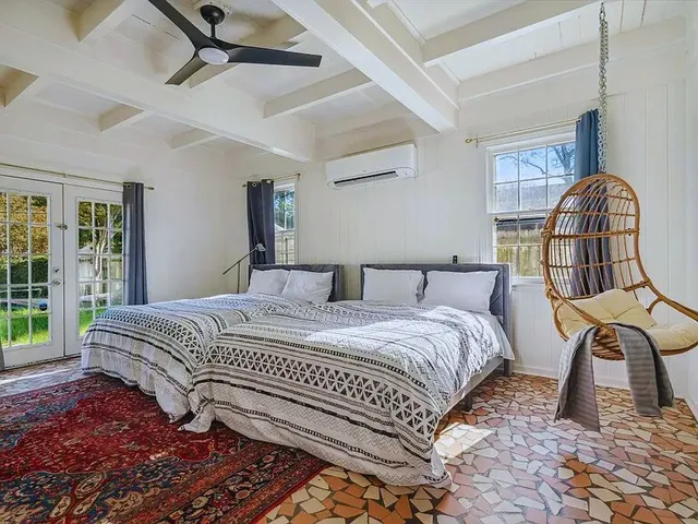 a bedroom with a bed a mirror on dresser and a large window