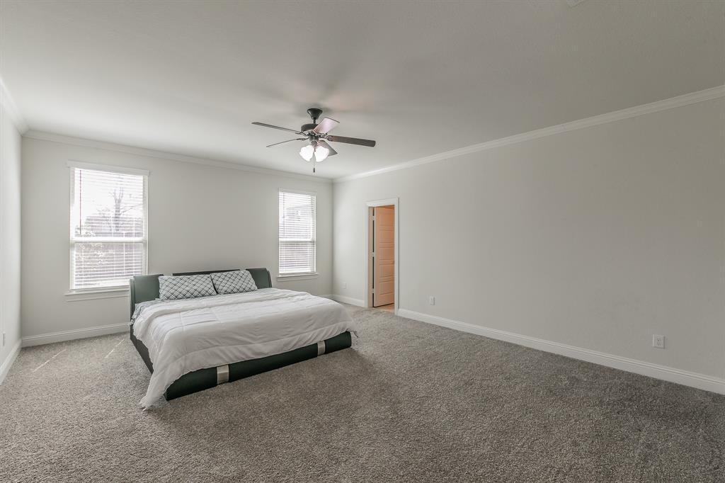 3424 Cimarron River Drive Prosper, TX 75078 - Photo 24 of 40 a spacious bedroom with a bed and a chandelier