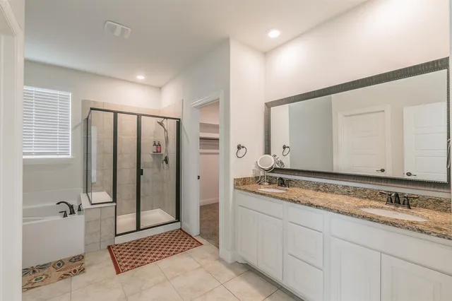 a spacious bathroom with a granite countertop sink a mirror and a bathtub