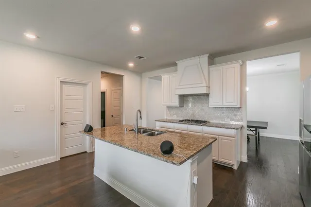 a open kitchen with stainless steel appliances granite countertop a sink dishwasher and a dining table with wooden floor