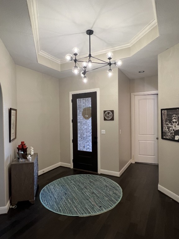 404 Peakside Circle Dripping Springs, TX 78620 - Photo 2 of 9 Foyer entrance featuring ornamental molding, dark wood-style flooring, a raised ceiling, and a chandelier