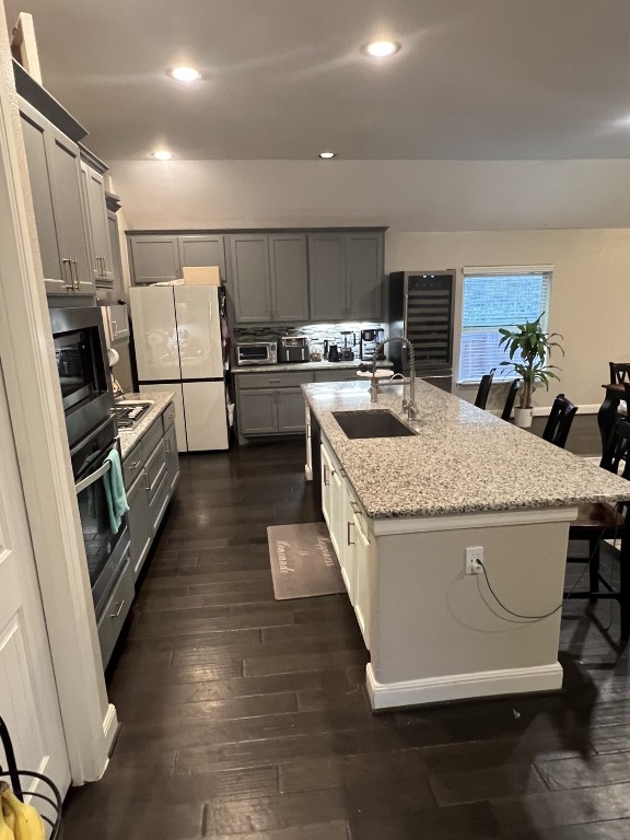 404 Peakside Circle Dripping Springs, TX 78620 - Photo 4 of 9 Kitchen featuring a breakfast bar, light stone countertops, recessed lighting, gray cabinetry, and a kitchen island with sink
