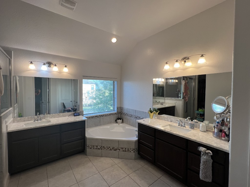 404 Peakside Circle Dripping Springs, TX 78620 - Photo 7 of 9 Bathroom with lofted ceiling, a bath, two vanities, light tile patterned floors, and recessed lighting