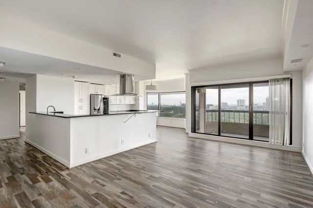 a view of kitchen with stainless steel appliances wooden floor and window