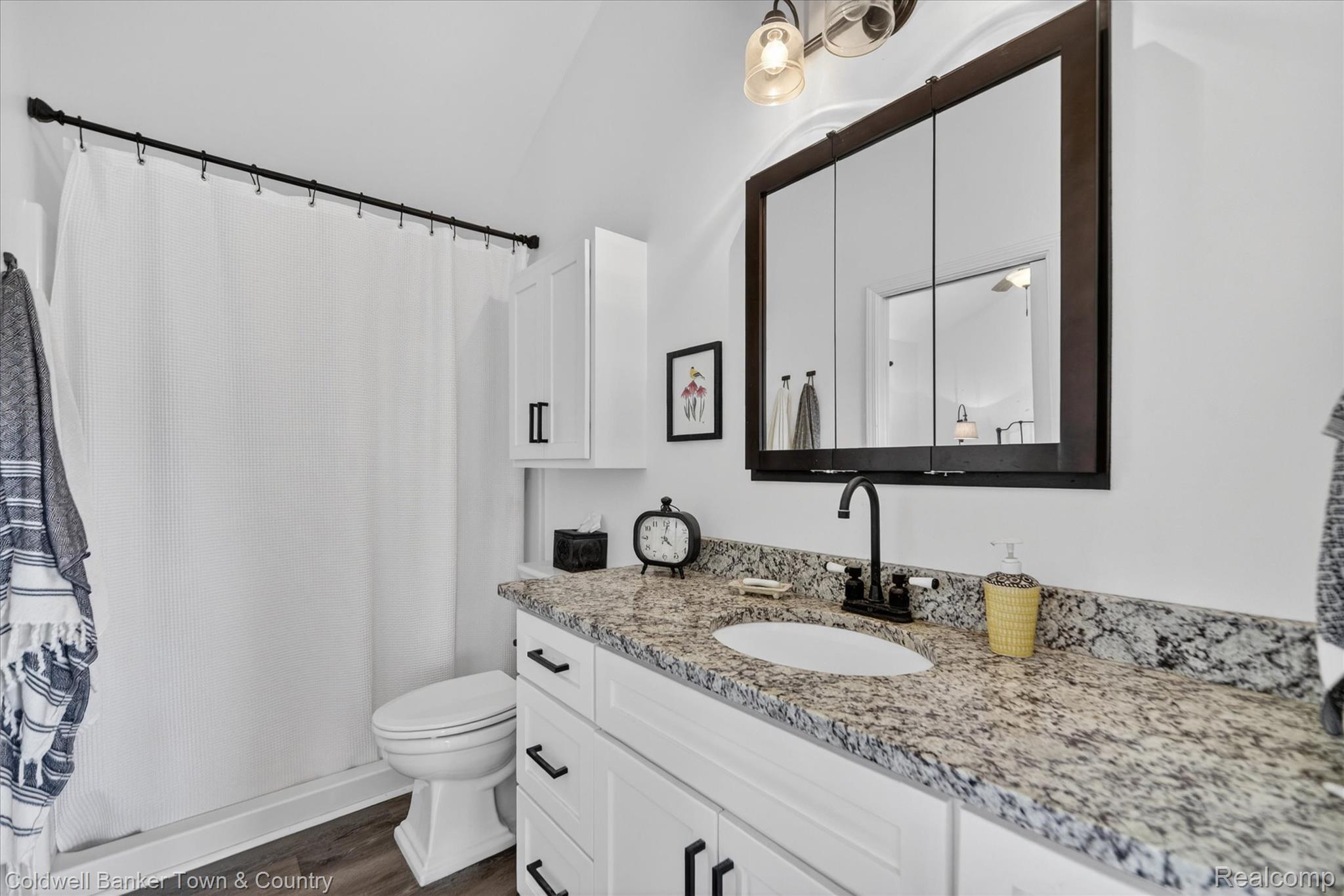 918 Gray Fox Court Howell, MI 48843 - Photo 59 of 84 Bathroom featuring a white vanity with black hardware, stone countertop, undermount sink, and matte black faucet