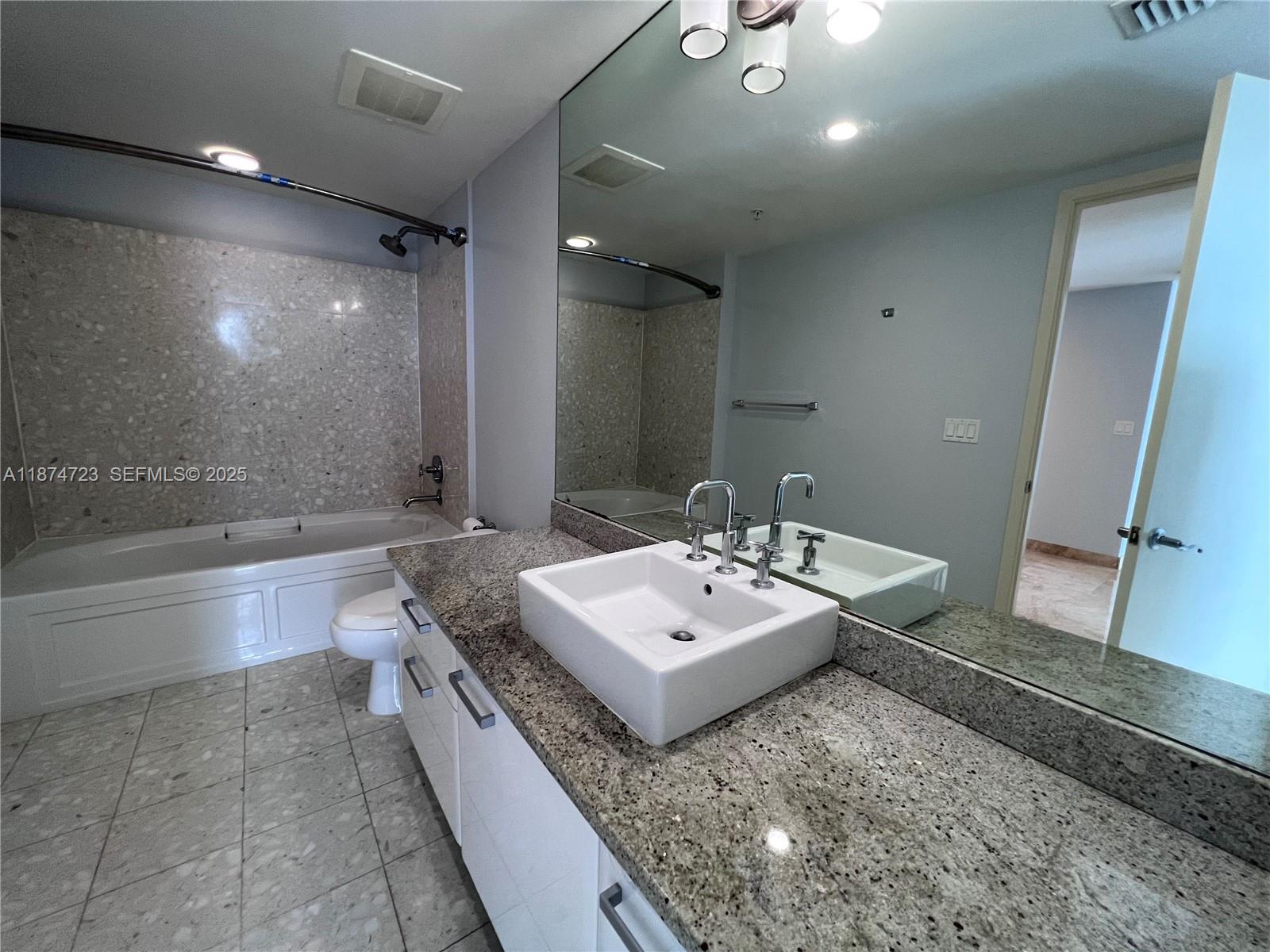 185 Southwest 7th Street, Unit 4204 Miami, FL 33130 - Photo 16 of 32 a spacious bathroom with a granite countertop sink a mirror and a bathtub