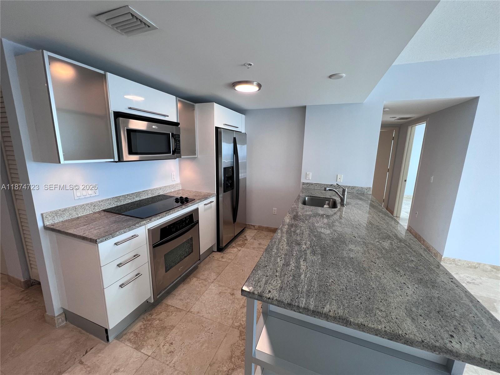 185 Southwest 7th Street, Unit 4204 Miami, FL 33130 - Photo 5 of 32 a kitchen with stainless steel appliances kitchen island granite countertop a stove and a microwave