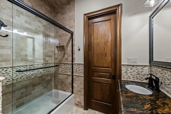 a bathroom with a double vanity sink a large mirror and shower