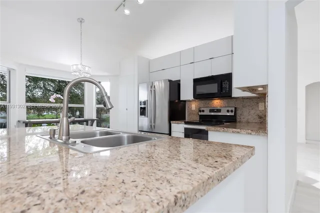 a view of a kitchen with kitchen island a sink and a refrigerator