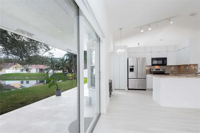 a view of a kitchen with stainless steel appliances kitchen island a refrigerator and a sink