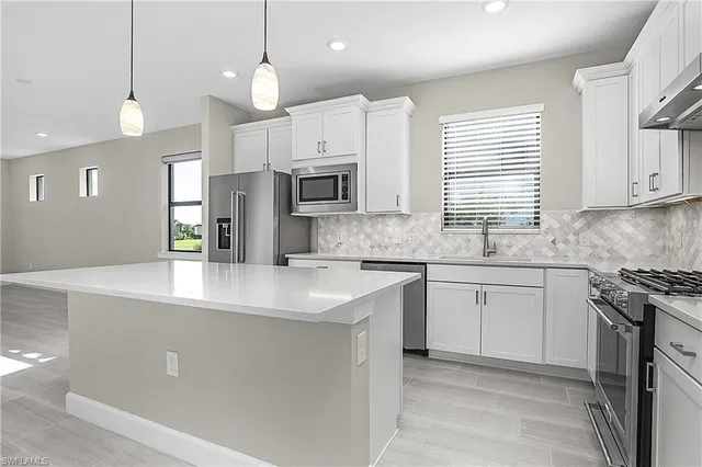 a kitchen with stainless steel appliances granite countertop a sink a stove a refrigerator and island with wooden floor