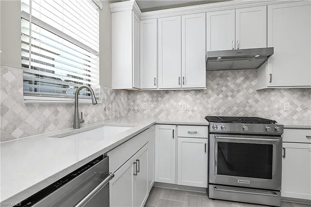 a kitchen with granite countertop white cabinets and a stove