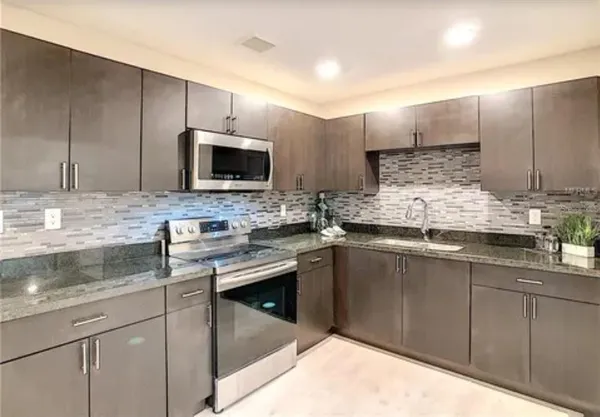 a kitchen with kitchen island granite countertop a sink stainless steel appliances and cabinets