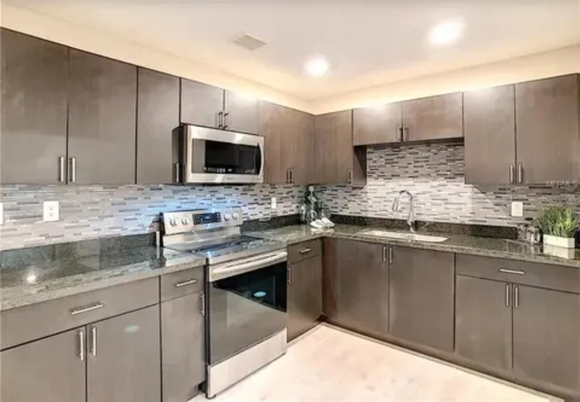 a kitchen with kitchen island granite countertop a sink stainless steel appliances and cabinets