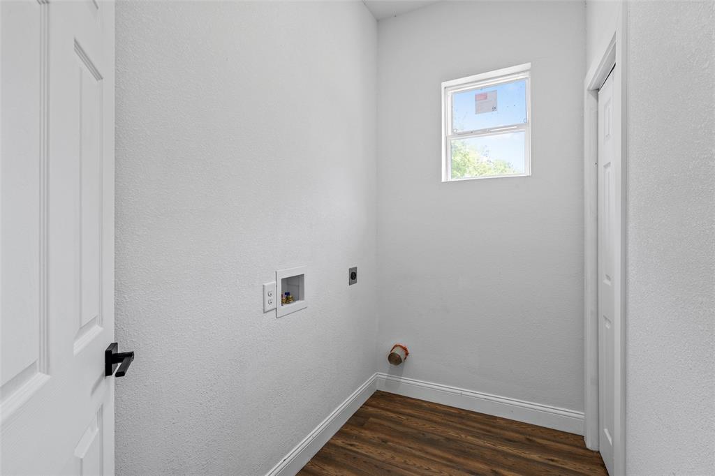 2023 Bosque Boulevard Waco, TX 76707 - Photo 11 of 26 Dedicated utility space featuring a window, wood-finish flooring, white baseboards, and a white paneled door with black hardware