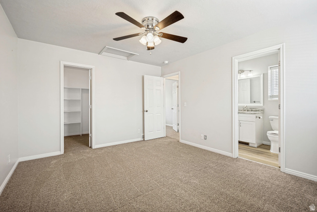 5529 Ridge Hollow Way Kearns, UT 84118 - Photo 14 of 23 Carpeted interior space featuring a ceiling fan with integrated lighting, a built-in closet with shelving, and access to a bathroom with a vanity, mirror, and toilet