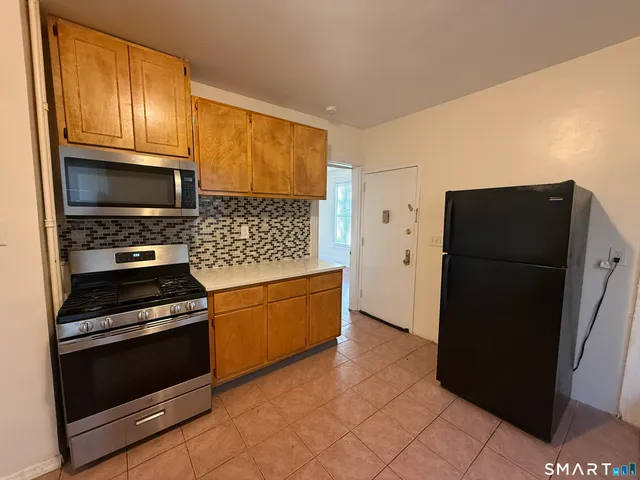 a kitchen with granite countertop a refrigerator and a stove top oven