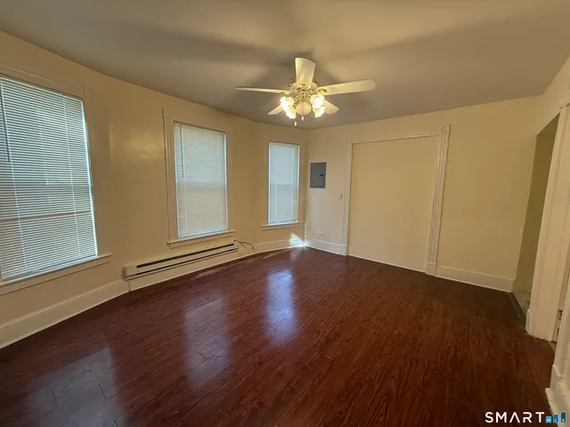 a view of an empty room with wooden floor and a window