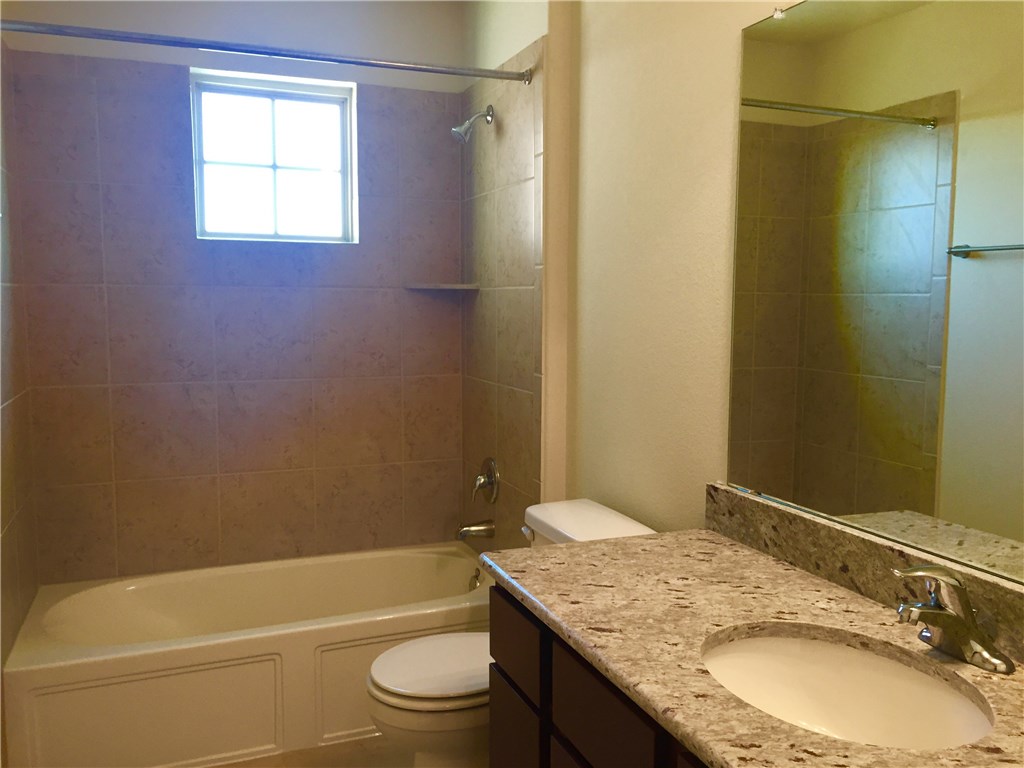 3451 Mayfield Ranch Boulevard, Unit 703 Round Rock, TX 78681 - Photo 20 of 23 a bathroom with a granite countertop sink toilet and shower