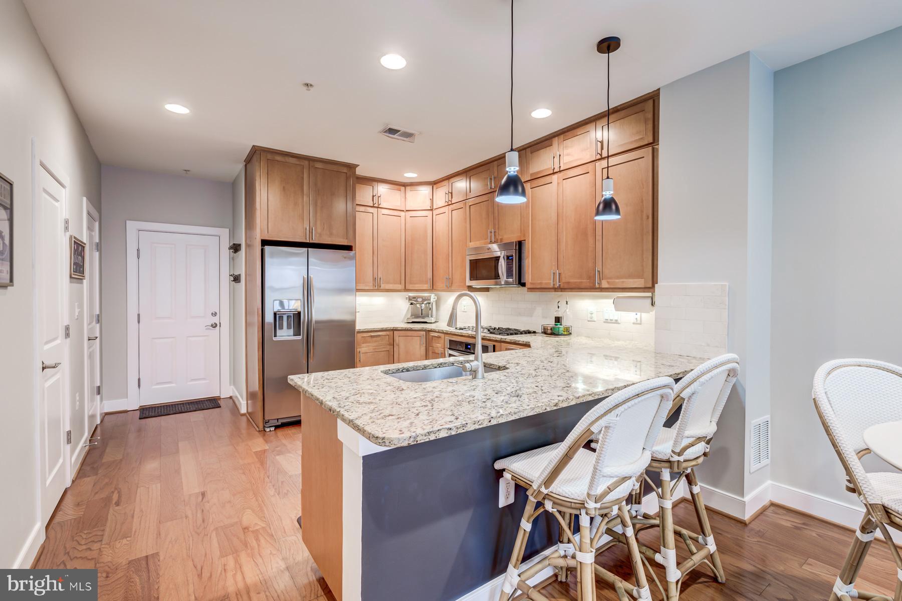 2207 Main Line Boulevard, Unit 101 Alexandria, VA 22301 - Photo 11 of 46 a kitchen with granite countertop a table chairs refrigerator and microwave