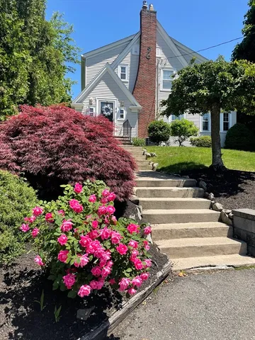 a front view of house with a lot of flowers