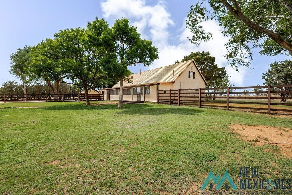 1131 Curry Road North Clovis, NM 88101 - Photo 50 of 69 Expansive green lawn surrounds a light-colored stucco residence featuring a gabled roofline and a screened-in porch