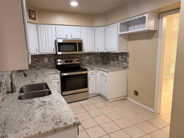 a kitchen with granite countertop a sink a stove top oven and refrigerator
