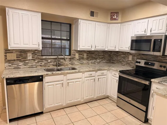 a kitchen with granite countertop white cabinets sink and stainless steel appliances
