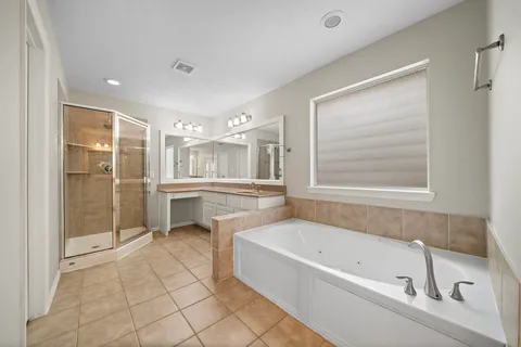 a bathroom with a tub sink shower and mirror
