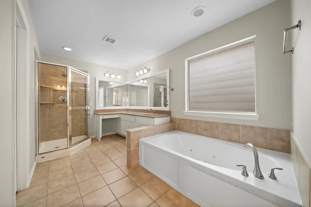 a bathroom with a tub sink shower and mirror