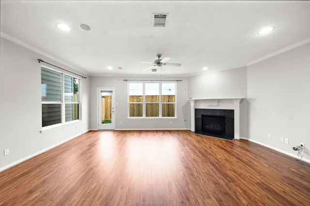 a view of an empty room with wooden floor fireplace and a window