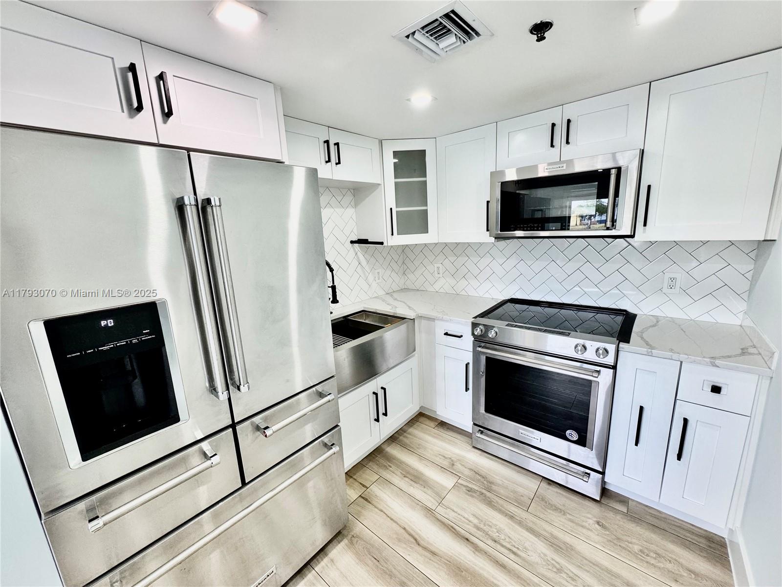 2415 Northwest 16th St Road, Unit 101 Miami, FL 33125 - Photo 15 of 36 a kitchen with stainless steel appliances a stove a microwave and a refrigerator