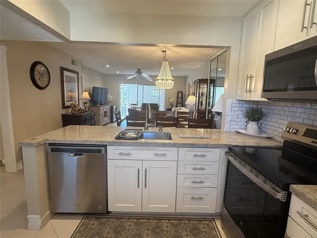 a kitchen with stainless steel appliances granite countertop a sink a stove a microwave a counter top and cabinets