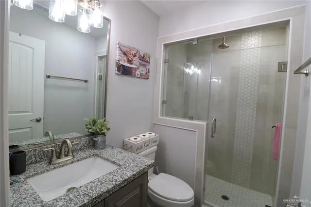 a bathroom with a granite countertop sink a toilet and shower