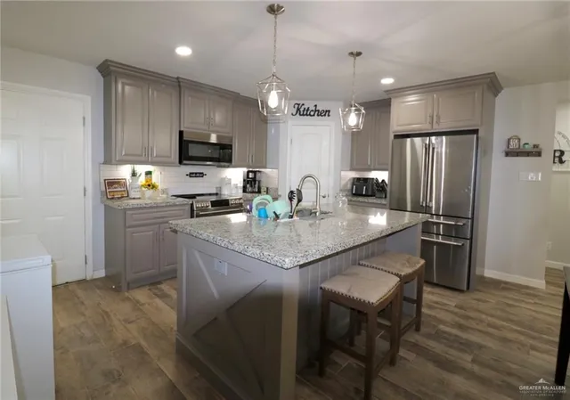 a kitchen with refrigerator a sink and chairs