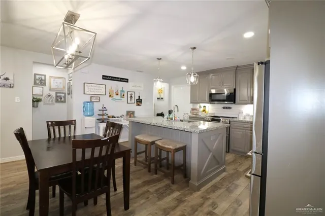 a kitchen with kitchen island a dining table chairs and white cabinets