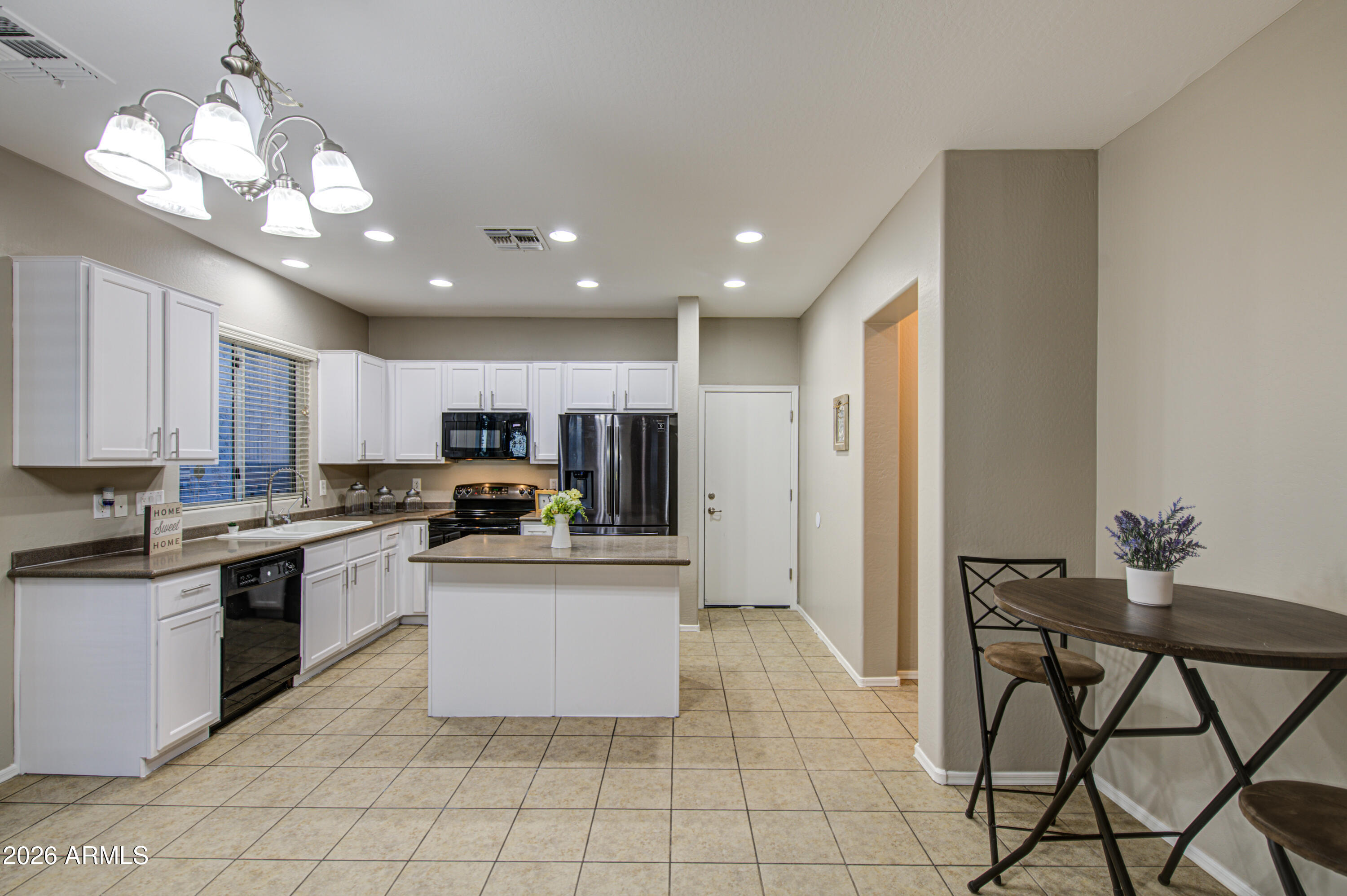 7759 West Monte Vista Road Phoenix, AZ 85035 - Photo 10 of 43 a kitchen with stainless steel appliances granite countertop a stove top oven a refrigerator a sink and a dining table with white cabinets